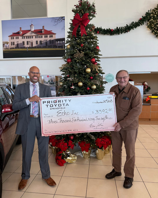 Two men from Priority Toyota holding a giant check